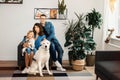 Happy caucasian family mother, father and daughter sitting at home near in living room decorated by trees in pots with their big Royalty Free Stock Photo