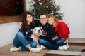 Happy caucasian family mother, father and daughter sitting at home near small christmas tree with their big white dog. Family Royalty Free Stock Photo