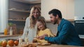 Happy Caucasian family preparing breakfast together talking at home kitchen mother hold glasses with milk little Royalty Free Stock Photo