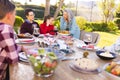 Happy caucasian family sitting at table and eating dinner together in sunny garden Royalty Free Stock Photo