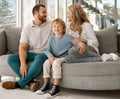 Happy caucasian family of three looking relaxed while sitting and bonding on the sofa together. Adorable little blonde Royalty Free Stock Photo