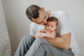 Happy Caucasian father holding newborn baby on laps knees. Man parent embracing kissing child daughter son. Authentic lifestyle Royalty Free Stock Photo