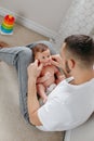 Happy Caucasian father holding newborn baby on laps knees. Man parent embracing rocking child daughter son. Authentic lifestyle Royalty Free Stock Photo