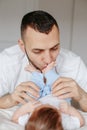 Happy Caucasian father holding a newborn baby. Man parent hugging kissing his child daughter son feet. Authentic lifestyle candid Royalty Free Stock Photo