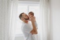 Happy Caucasian father kissing newborn baby. Male man parent holding rocking child daughter son in his hands. Authentic lifestyle Royalty Free Stock Photo