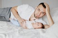 Happy Caucasian father lying with newborn baby in bedroom at home. Man parent holding child daughter son. Authentic lifestyle Royalty Free Stock Photo