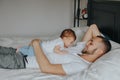 Happy Caucasian father lying with newborn baby in bedroom at home. Man parent holding child daughter son. Authentic lifestyle Royalty Free Stock Photo