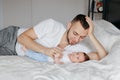 Happy Caucasian father lying with newborn baby in bedroom at home. Man parent holding child daughter son. Authentic lifestyle Royalty Free Stock Photo