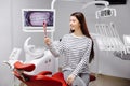 Happy caucasian female patient looking at mirror after dental treatment in clinic. Cheerful woman sitting in chair in dental Royalty Free Stock Photo