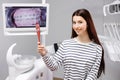 Happy caucasian female patient looking at mirror after dental treatment in clinic. Cheerful woman sitting in chair in dental Royalty Free Stock Photo