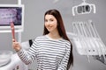 Happy caucasian female patient looking at mirror after dental treatment in clinic. Cheerful woman sitting in chair in dental Royalty Free Stock Photo