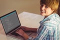 Happy caucasian female programmer siting at desk, using laptop with coding on screen Royalty Free Stock Photo