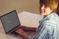 Happy caucasian female programmer sitting at desk, using laptop with coding on screen Royalty Free Stock Photo