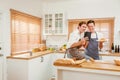 Happy Caucasian gay couple cooking together in the kitchen while watching how to cook on a digital tablet with fun and a smile. Royalty Free Stock Photo