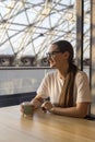 Beautiful girl in glasses drinks coffee at a cafe table