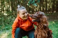 Happy caucasian girl hiker hiker walks with her cute Irish Setter dog on a walk in a summer forest Royalty Free Stock Photo