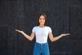 Happy Caucasian girl holding arms at her sides like a scale and standing in a white T-shirt Royalty Free Stock Photo