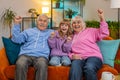 Happy Caucasian grandparents child girl granddaughter watching TV celebrating success winning goal Royalty Free Stock Photo