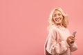 Happy caucasian lady with newest smartphone looking back at free space over pink studio background, panorama