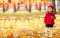 Happy caucasian little girl in a red coat and beret in the park with a red apple in her hands Royalty Free Stock Photo