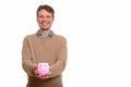 Happy Caucasian man holding piggy bank and looking at camera Royalty Free Stock Photo