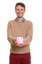 Happy Caucasian man holding piggy bank while smiling Royalty Free Stock Photo