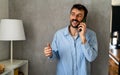 Happy caucasian man laughing during smartphone conversation. Royalty Free Stock Photo