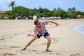 Happy caucasian man playing on beach throwing stones on ocean, Bali