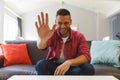 Happy caucasian man sitting on couch having video call in living room, smiling and waving Royalty Free Stock Photo