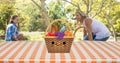 Happy caucasian mother and daughter with picnic blanket and basket enjoying in park