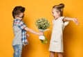Happy caucasian people boy gives a flowers to his girlfriend isolated over yellow background. Royalty Free Stock Photo