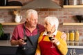 Happy caucasian senior couple cooking, drinking wine and embracing in kitchen Royalty Free Stock Photo