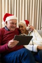 Happy caucasian senior couple having christmas tablet video call embracing at home, copy space