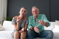 Happy caucasian senior couple in living room, on couch making video call, gesturing and smiling