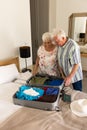 Happy caucasian senior couple packing suitcase and embracing in sunny bedroom at home Royalty Free Stock Photo