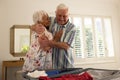 Happy caucasian senior couple packing suitcase and embracing in sunny bedroom at home Royalty Free Stock Photo