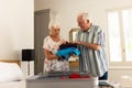 Happy caucasian senior couple packing suitcase in sunny bedroom at home Royalty Free Stock Photo