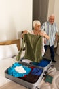 Happy caucasian senior couple packing suitcase in sunny bedroom at home Royalty Free Stock Photo