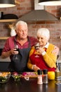 Happy caucasian senior couple preparing vegetables, drinking wine, embracing in kitchen, copy space Royalty Free Stock Photo