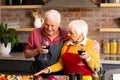 Happy caucasian senior couple preparing vegetables, drinking wine and embracing in kitchen Royalty Free Stock Photo