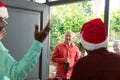 Happy caucasian senior couple with wine coming to visit their diverse friends at christmas time Royalty Free Stock Photo