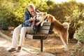 Happy caucasian senior man with beard in glasses gives to sniff his hand to dog, training in park, enjoy love Royalty Free Stock Photo