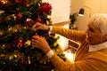 Happy caucasian senior woman decorating christmas tree in living room at home Royalty Free Stock Photo