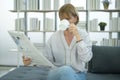 Happy  Caucasian senior woman  is relaxing , reading newspaper in living room Royalty Free Stock Photo