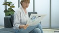 Happy  Caucasian senior woman  is relaxing , reading newspaper in living room Royalty Free Stock Photo