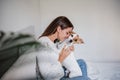 Happy caucasian woman at home cuddling on bed with cute jack russell dog. Pets, love and relax at home Royalty Free Stock Photo