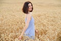 Happy caucasian woman walking at golden wheat field at sunrise. Cheerful girl enjoy autumn, smiling Royalty Free Stock Photo