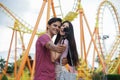 Happy Caucasian young couples take camera selfie photos together at theme park