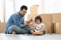 Happy Caucasian young father and little daughter enjoy coloring wooden toy house together on new home floor. Royalty Free Stock Photo