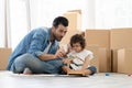 Happy Caucasian young father and little girl sitting on new home floor holding paintbrush to paint water color on wooden toy house Royalty Free Stock Photo